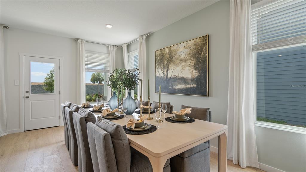 A dining room features a light wood table, grey upholstered chairs, and large windows — 3054 GRANITE RIDGE AVENUE, MINNEOLA, FL