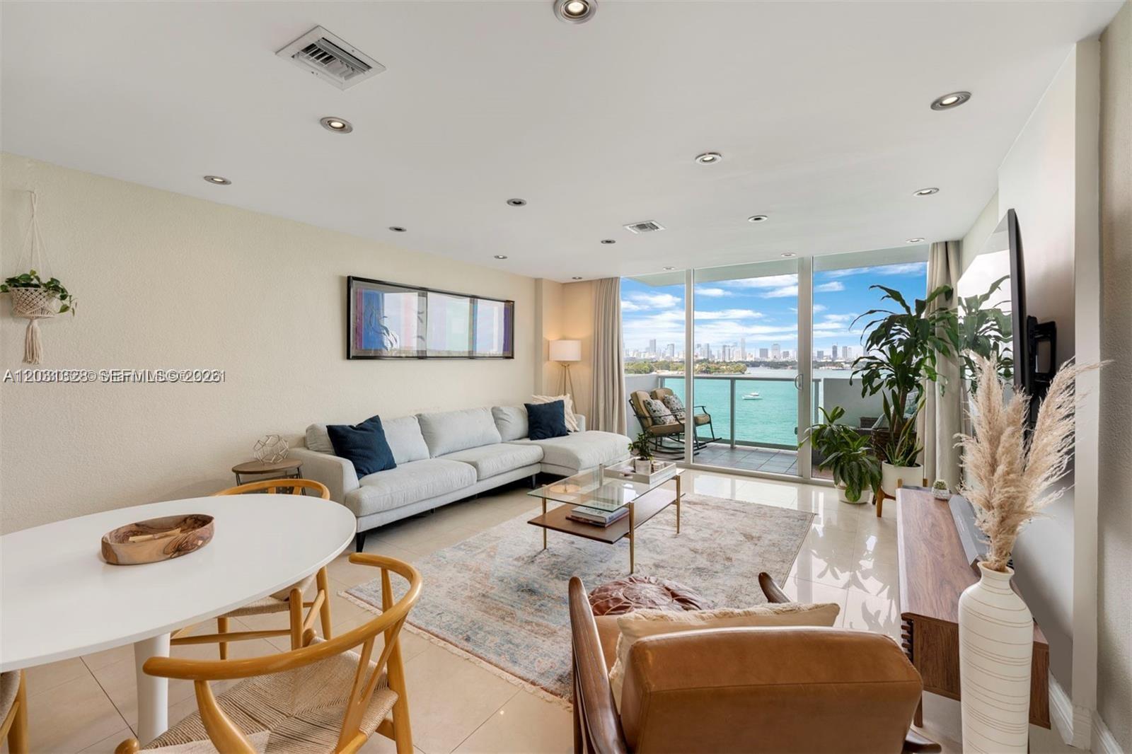 A living room features a sectional sofa, dining area, and balcony with a city view — 1200 West Ave # 725, Miami Beach FL 33139, MIAMI BEACH, FL