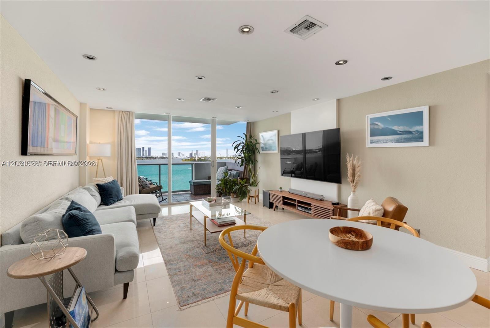A bright living and dining area features a balcony with water and city skyline views — 1200 West Ave # 725, Miami Beach FL 33139, MIAMI BEACH, FL