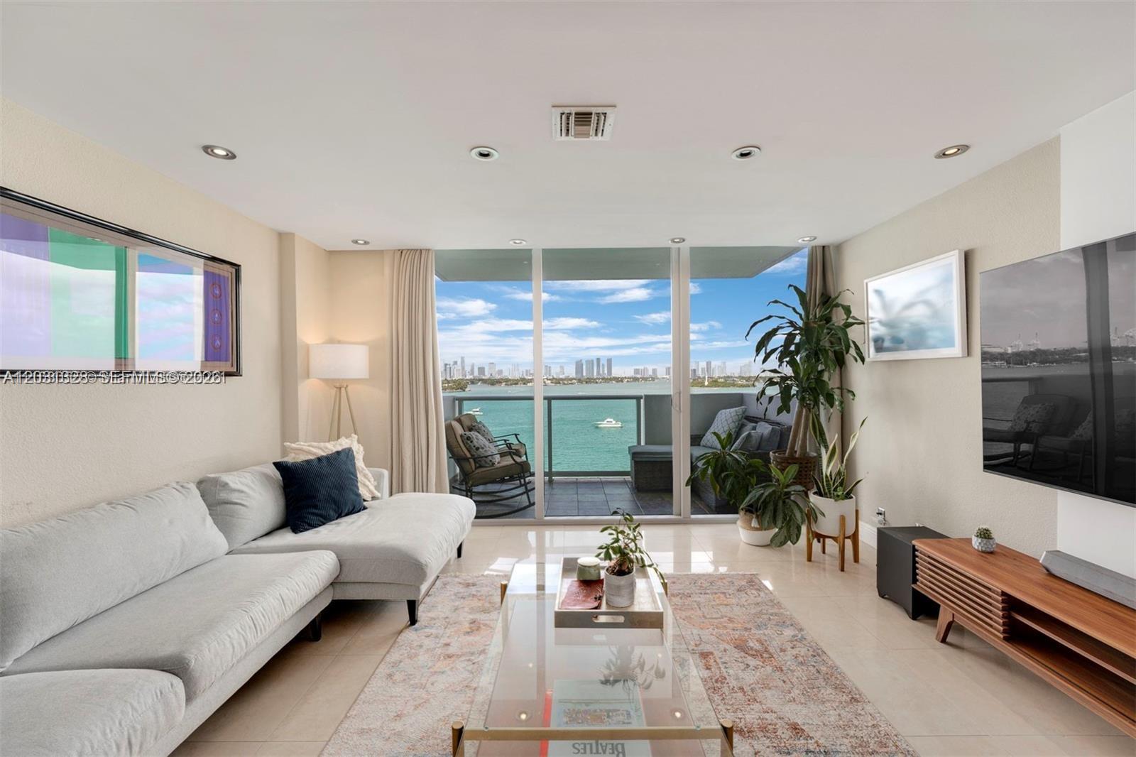 A living room with a sectional sofa, glass coffee table, and balcony overlooking the ocean — 1200 West Ave # 725, Miami Beach FL 33139, MIAMI BEACH, FL