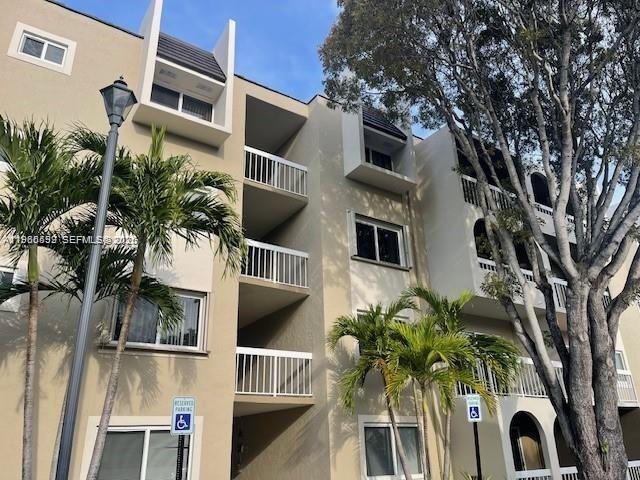 A multi-story apartment building exterior features beige stucco walls, balconies, and palm trees — 7732 Camino Real # F220, Miami FL 33143, MIAMI, FL