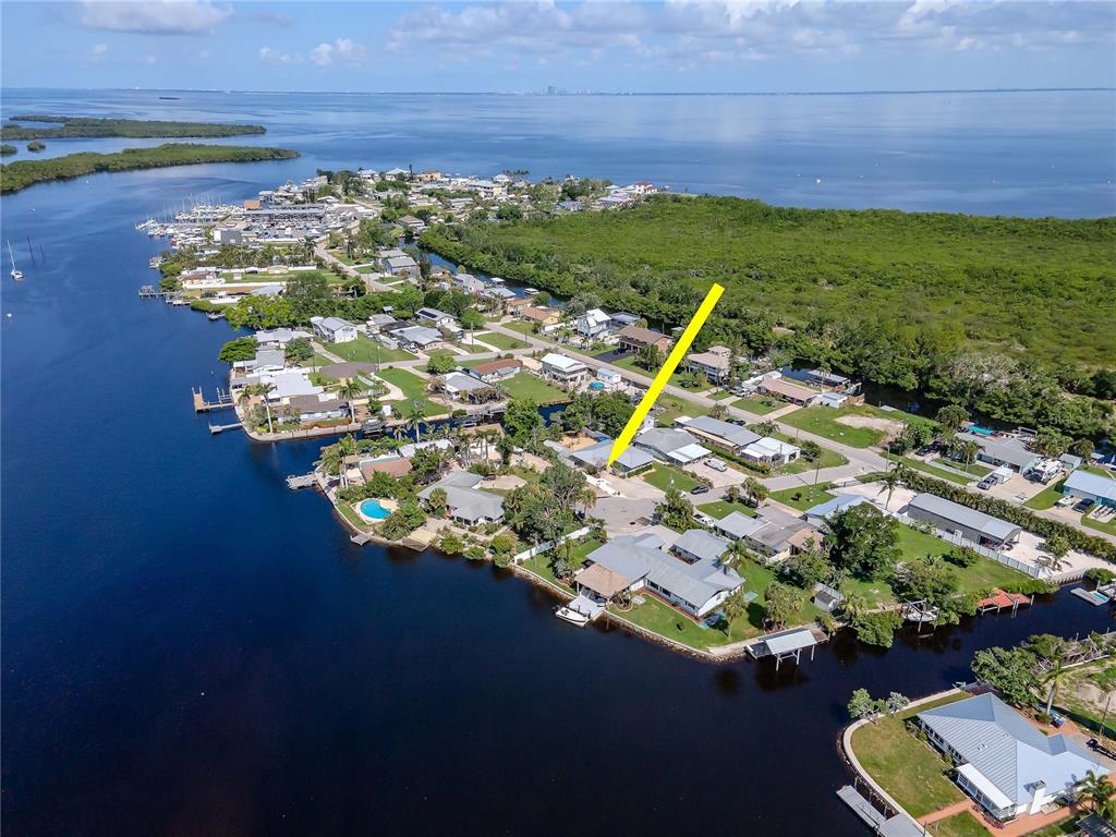 An aerial view shows a coastal neighborhood with a yellow arrow pointing to a house — 106 STEVEN STREET, RUSKIN, FL