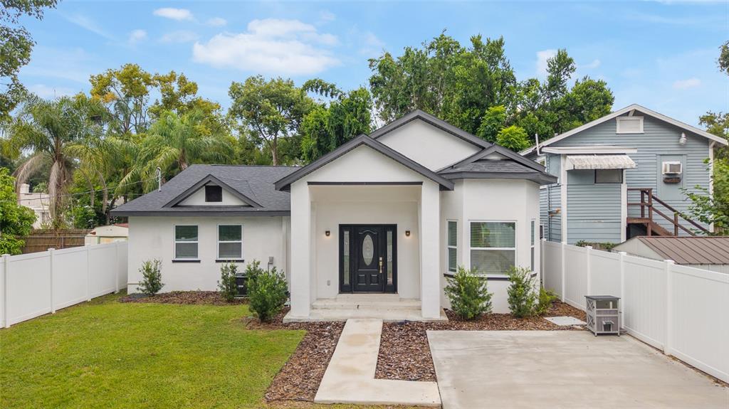 A white single-story house with a dark roof, black front door, and a concrete driveway — 914 E NORTH BAY STREET, TAMPA, FL