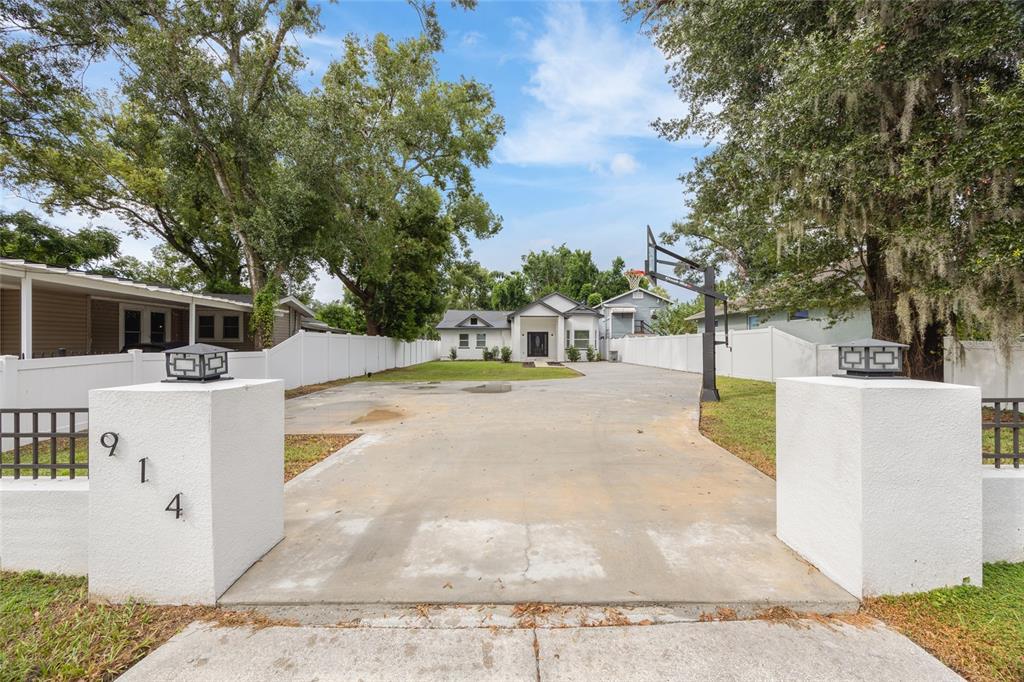 A long concrete driveway leads to a single-story house behind a white gated entrance — 914 E NORTH BAY STREET, TAMPA, FL