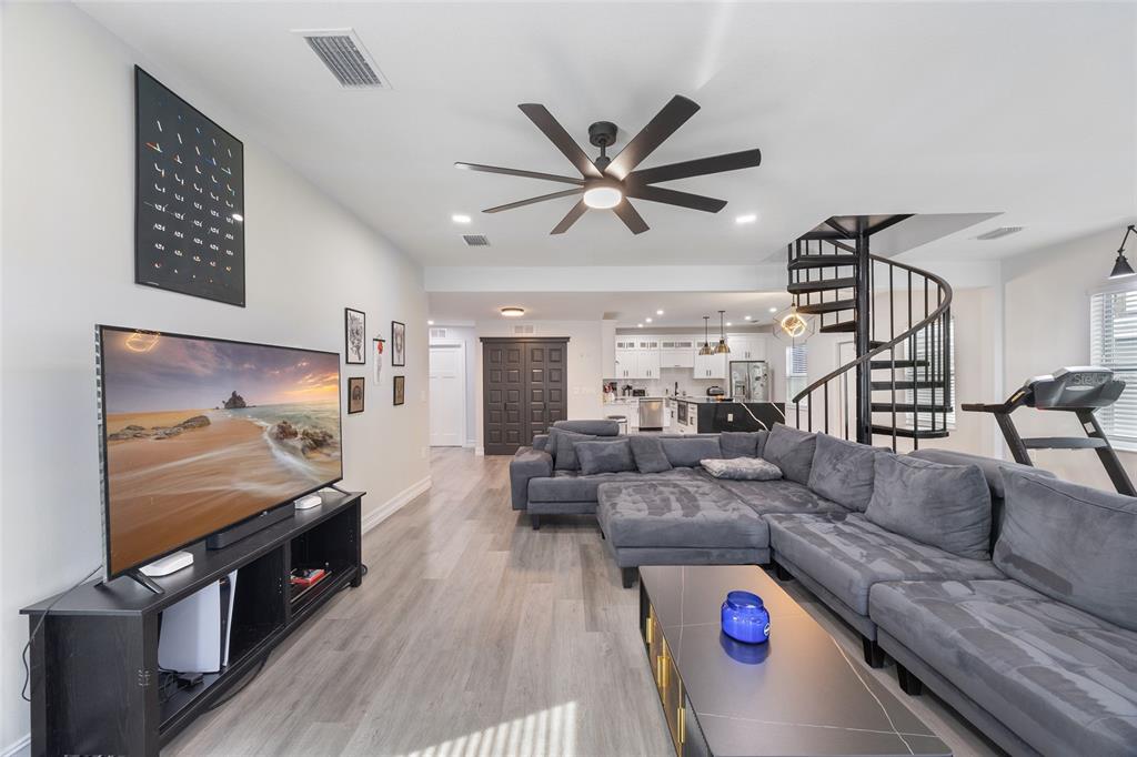 A living room features a large sectional sofa, a television, and a black spiral staircase — 914 E NORTH BAY STREET, TAMPA, FL