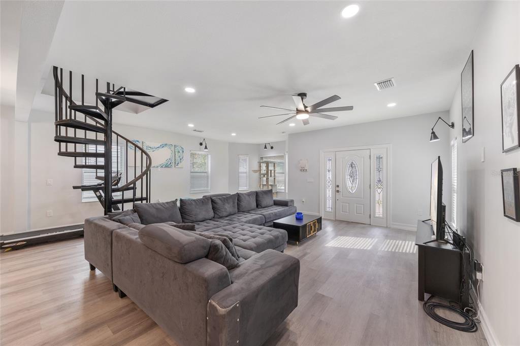 A living room features a large gray sectional sofa, a spiral staircase, and light flooring — 914 E NORTH BAY STREET, TAMPA, FL
