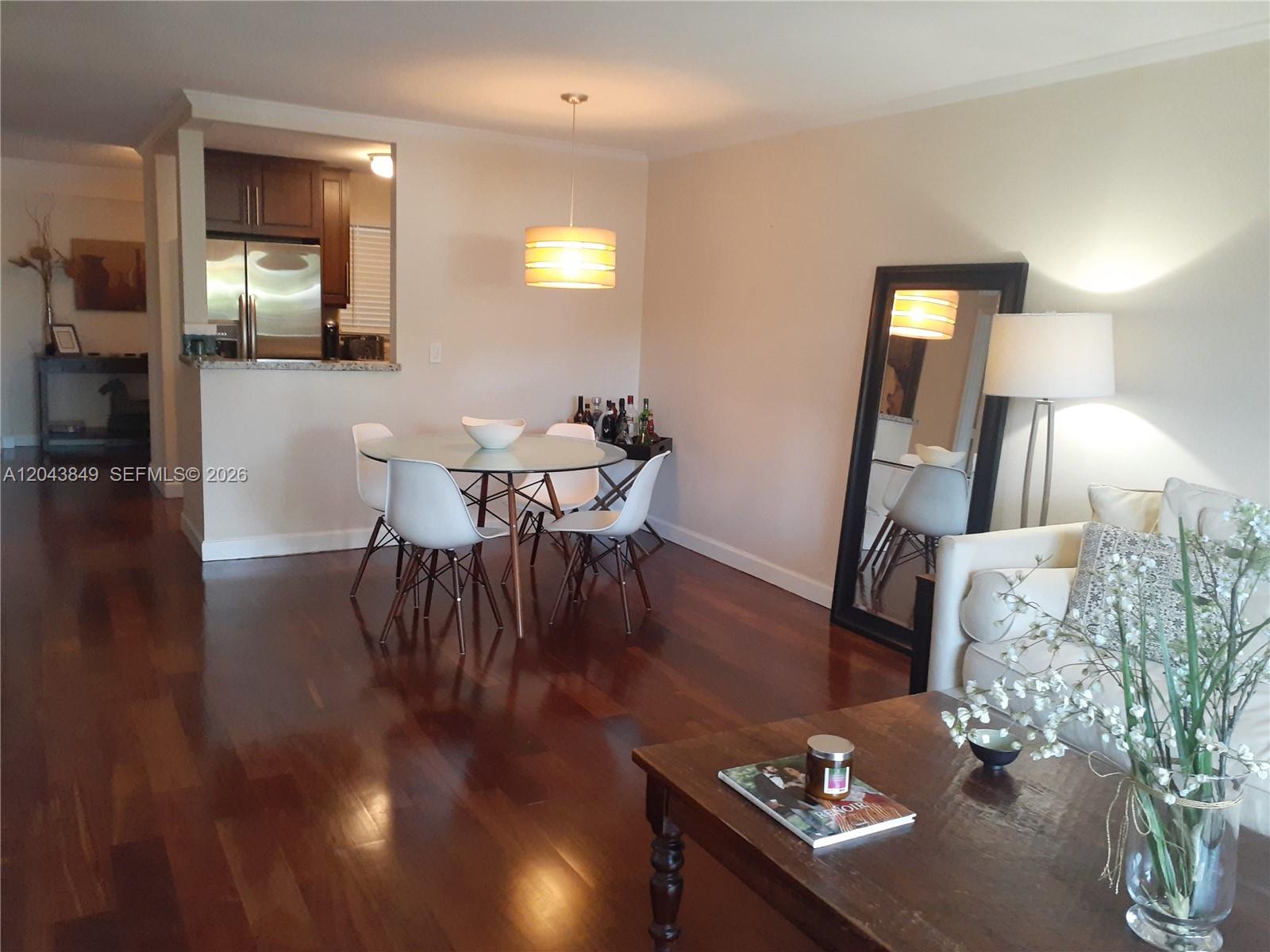 A dining area with a glass table and white chairs sits beside a living room — 1610 Lenox Ave # 301, Miami Beach FL 33139, MIAMI BEACH, FL