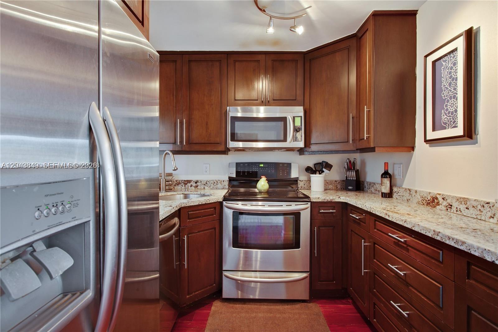 A kitchen features dark wood cabinets, stainless steel appliances, and granite countertops — 1610 Lenox Ave # 301, Miami Beach FL 33139, MIAMI BEACH, FL