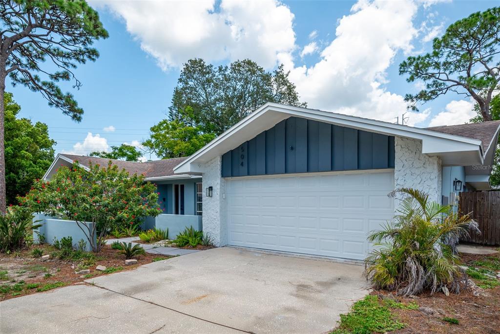 A single-story house with a white garage, blue siding, and a concrete driveway — 504 BAMBOO COURT, TARPON SPRINGS, FL