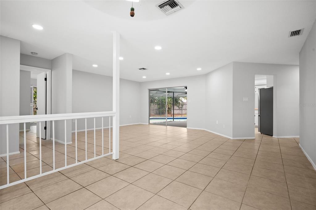 A spacious living area with light tile flooring, recessed lighting, and a sliding glass door — 504 BAMBOO COURT, TARPON SPRINGS, FL