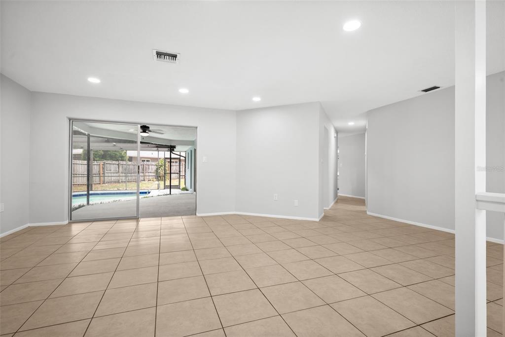 An empty room with light-colored tile flooring, recessed lighting, and a sliding glass door to a pool — 504 BAMBOO COURT, TARPON SPRINGS, FL