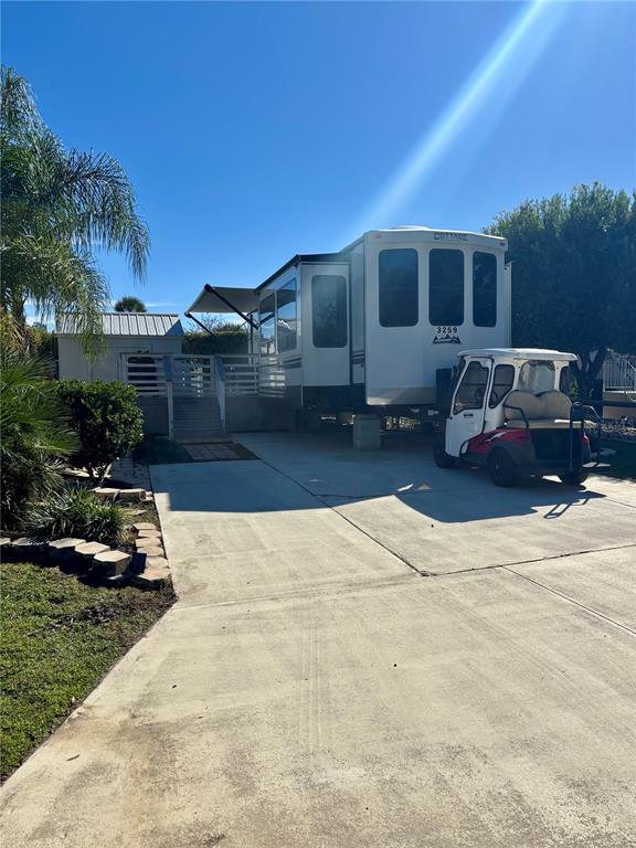 A white recreational vehicle and a golf cart are parked on a concrete driveway — 3259 NE 102ND AVENUE ROAD, SILVER SPRINGS, FL