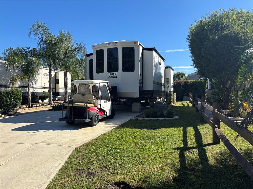 A golf cart is parked in front of a recreational vehicle on a paved driveway — 3259 NE 102ND AVENUE ROAD, SILVER SPRINGS, FL
