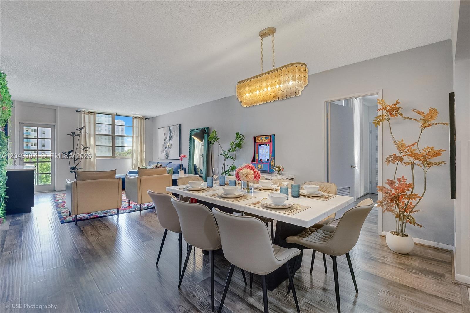 A dining area with a marble table and modern chairs sits adjacent to a living room — SUNNY ISLES BEACH, FL