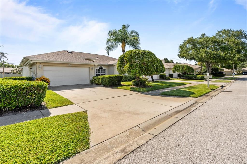 A single-story house with a two-car garage and manicured landscaping sits along a suburban street — 2788 COUNTRY WAY, CLEARWATER, FL