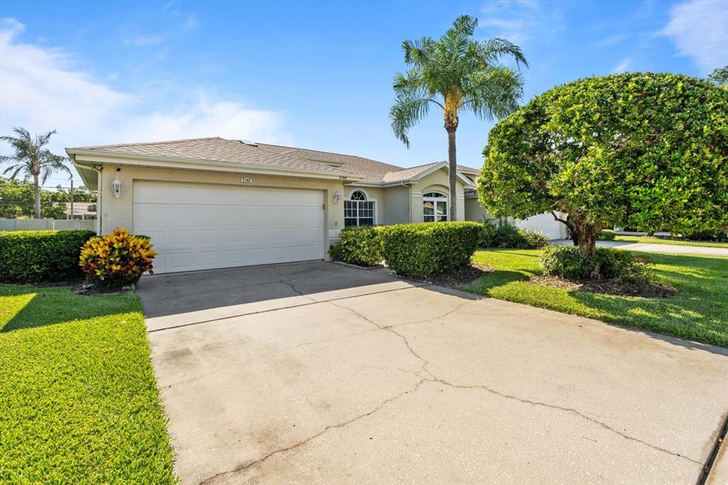A single-story house with a white garage door, concrete driveway, and landscaped front yard — 2788 COUNTRY WAY, CLEARWATER, FL
