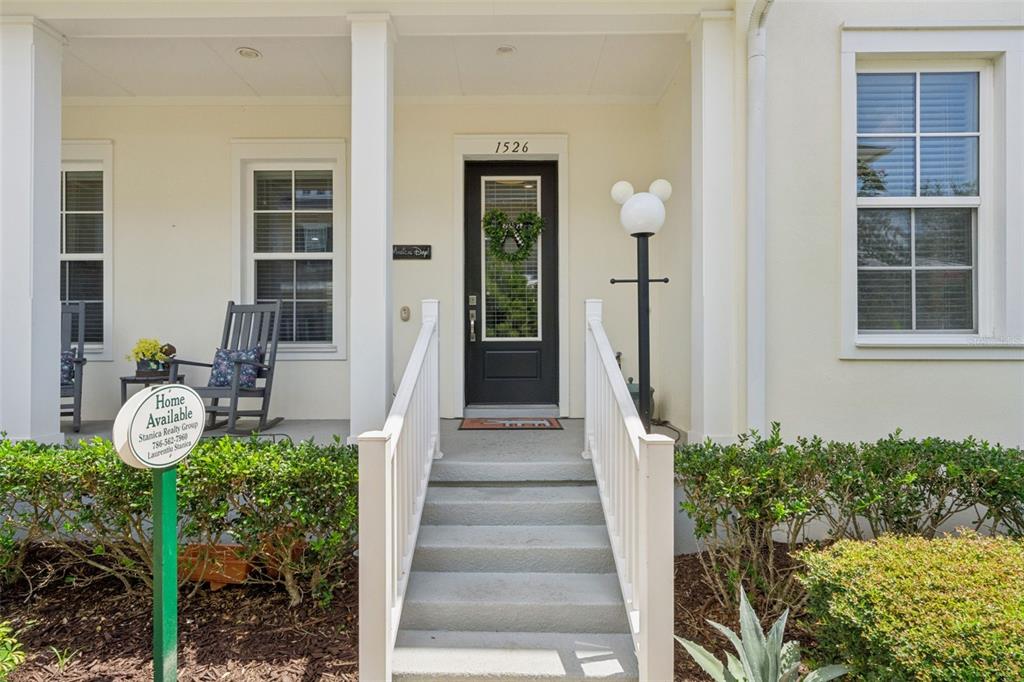 A front porch with stairs, a black door, and rocking chairs leads to a house entrance — 1526 RESOLUTE STREET, CELEBRATION, FL