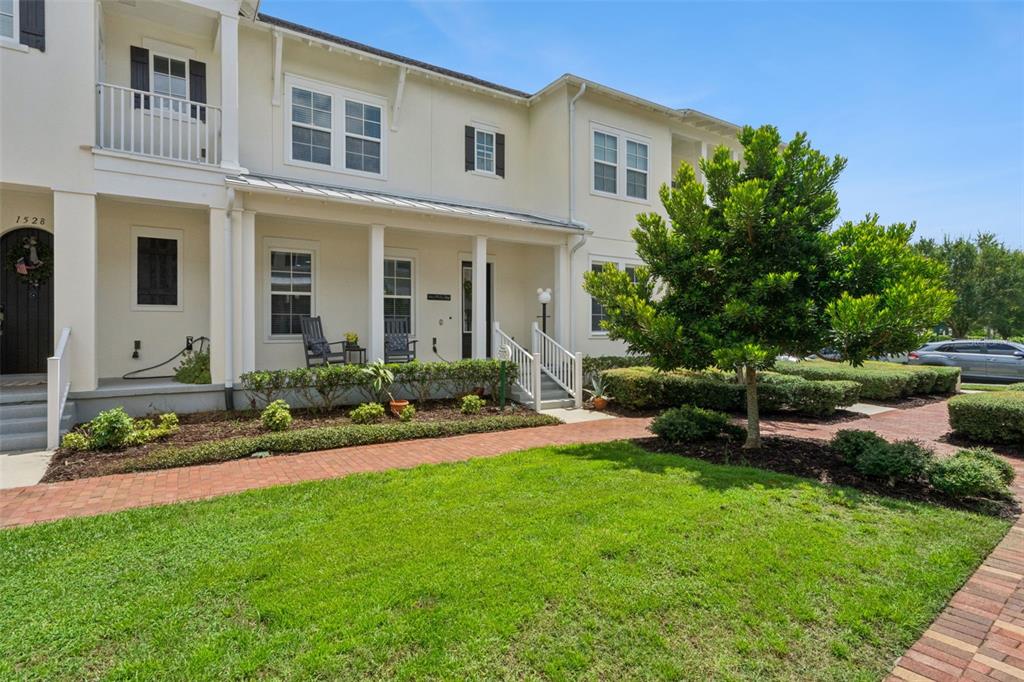 A two-story townhouse with a covered front porch, brick walkway, and manicured landscaping — 1526 RESOLUTE STREET, CELEBRATION, FL