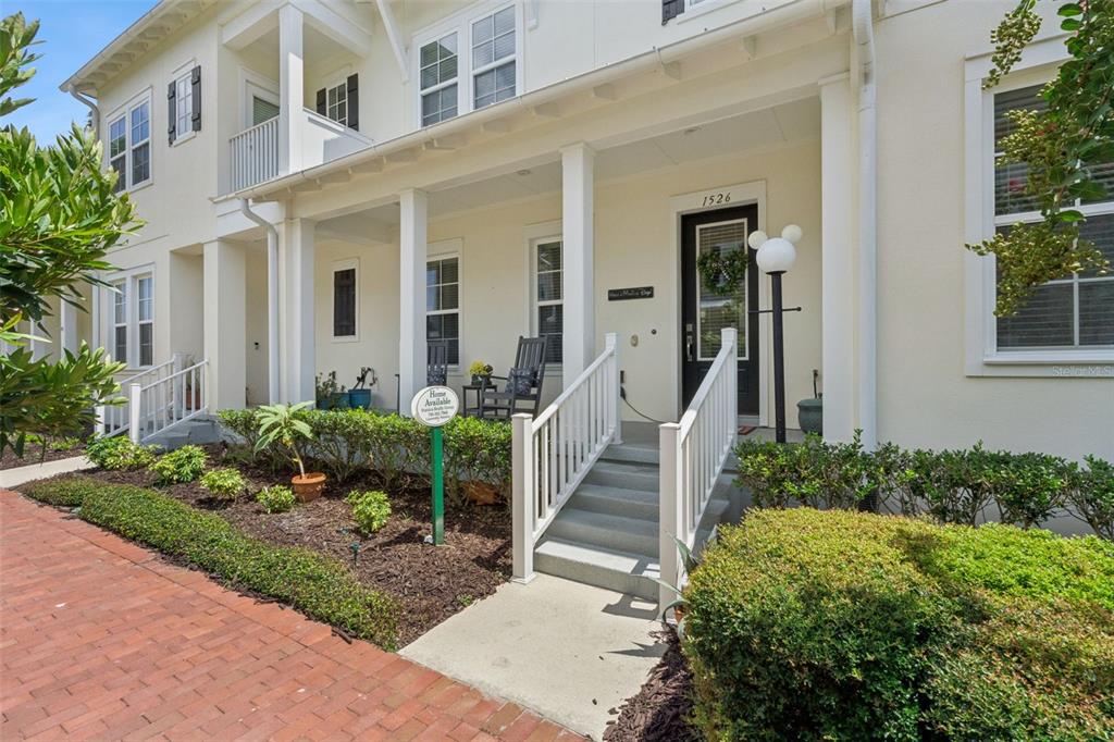 A two-story townhouse with a white exterior, a front porch, and a brick walkway — 1526 RESOLUTE STREET, CELEBRATION, FL
