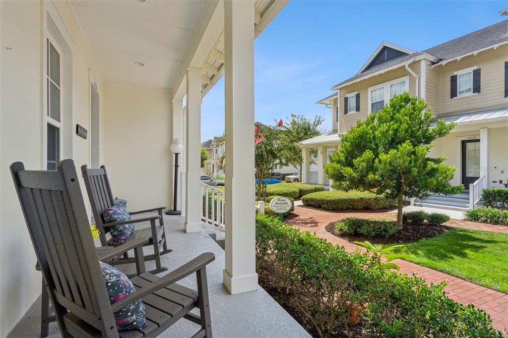 A covered front porch features two rocking chairs overlooking a landscaped courtyard and neighboring houses — 1526 RESOLUTE STREET, CELEBRATION, FL