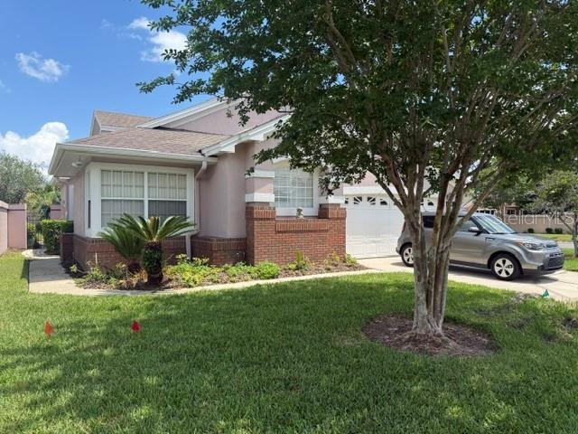 A single-story house with a brick facade, a tan exterior, and a parked silver SUV — 14453 WINDCHIME LANE, ORLANDO, FL