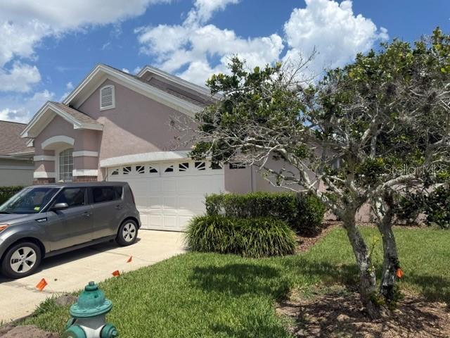 A gray car is parked in the driveway of a single-story house with a garage — 14453 WINDCHIME LANE, ORLANDO, FL