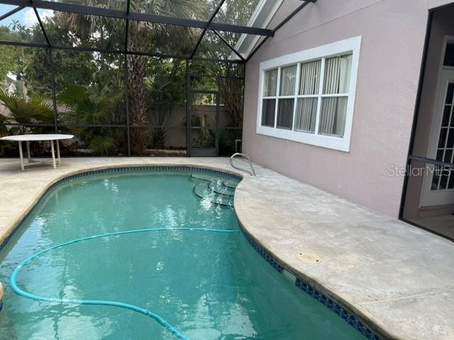 A screened-in patio features a swimming pool, concrete decking, and a white-framed window — 14453 WINDCHIME LANE, ORLANDO, FL