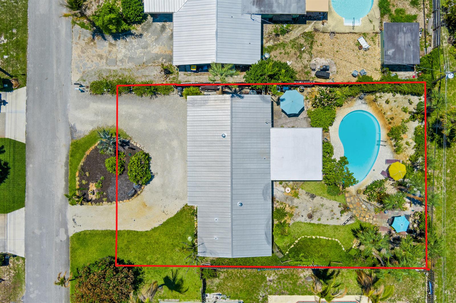 An aerial view shows a house with a metal roof, a pool, and a gravel driveway — 1644 NE Arch Avenue, Jensen Beach FL 34957, JENSEN BEACH, FL
