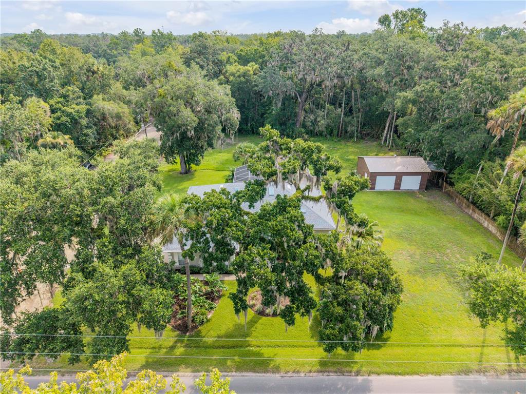 An aerial view shows a house with a large yard, mature trees, and a detached garage — 707 CORBIN PARK ROAD, NEW SMYRNA BEACH, FL