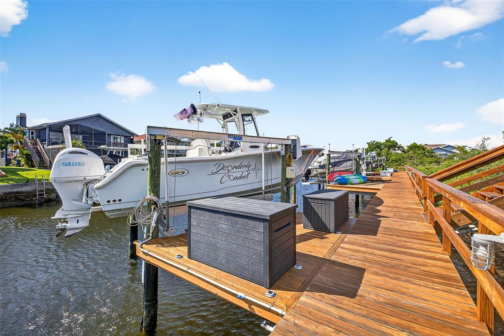 A white boat named Disorderly Conduct is lifted on a dock beside a wooden walkway — 4516 SEAGULL DRIVE UNIT 519, NEW PORT RICHEY, FL