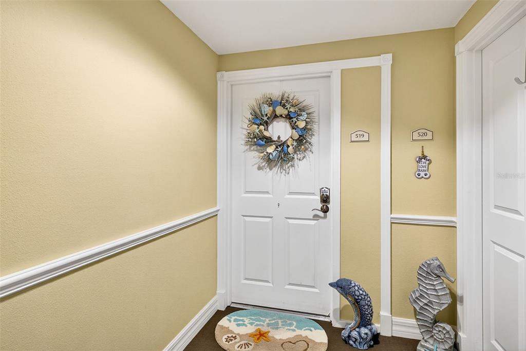 A hallway features a white door with a wreath, room numbers, and coastal-themed decor — 4516 SEAGULL DRIVE UNIT 519, NEW PORT RICHEY, FL