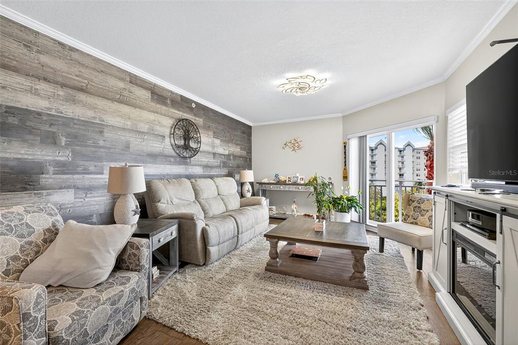 A living room features a wood-plank accent wall, a sofa, armchairs, and a sliding glass door — 4516 SEAGULL DRIVE UNIT 519, NEW PORT RICHEY, FL