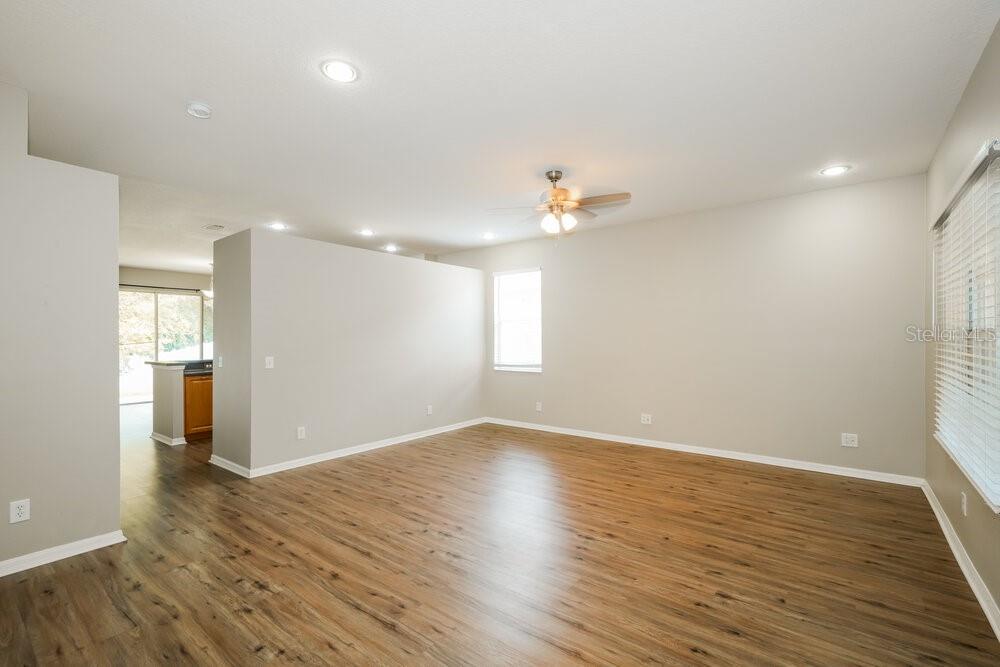 A living room with light-colored walls, wood-look flooring, a ceiling fan, and a window — 12923 TERRACE SPRINGS DRIVE, TEMPLE TERRACE, FL