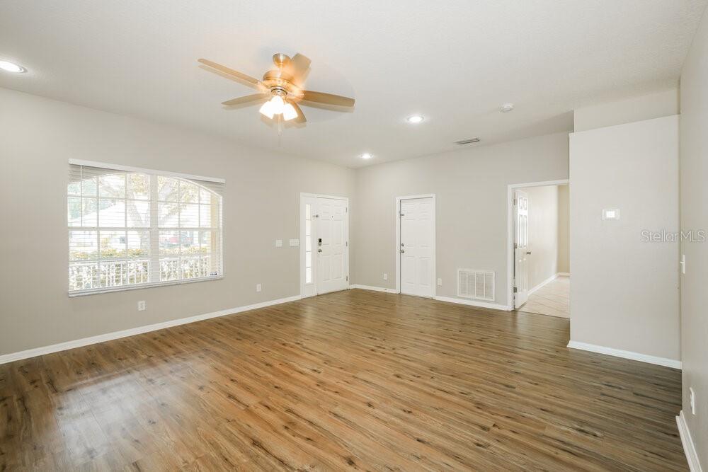 An empty room with light wood-look flooring, a ceiling fan, and white walls — 12923 TERRACE SPRINGS DRIVE, TEMPLE TERRACE, FL