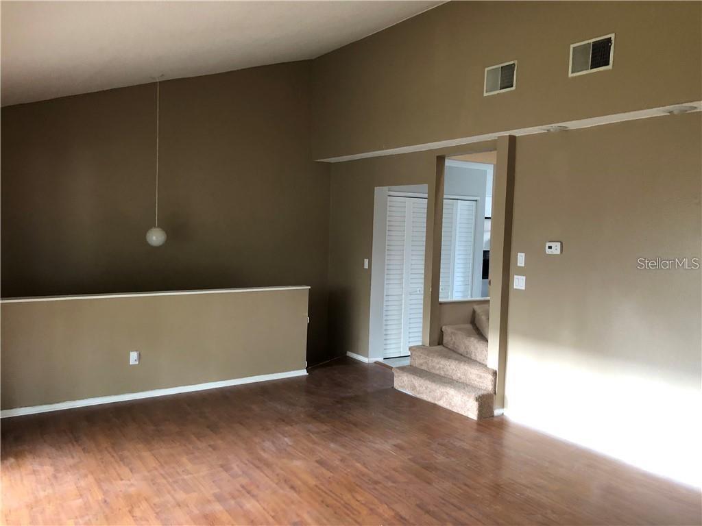 A room with wood-look flooring, a half-wall, and carpeted stairs leading to an upper level — 5453 SWEETWATER TERRACE CIRCLE, TAMPA, FL
