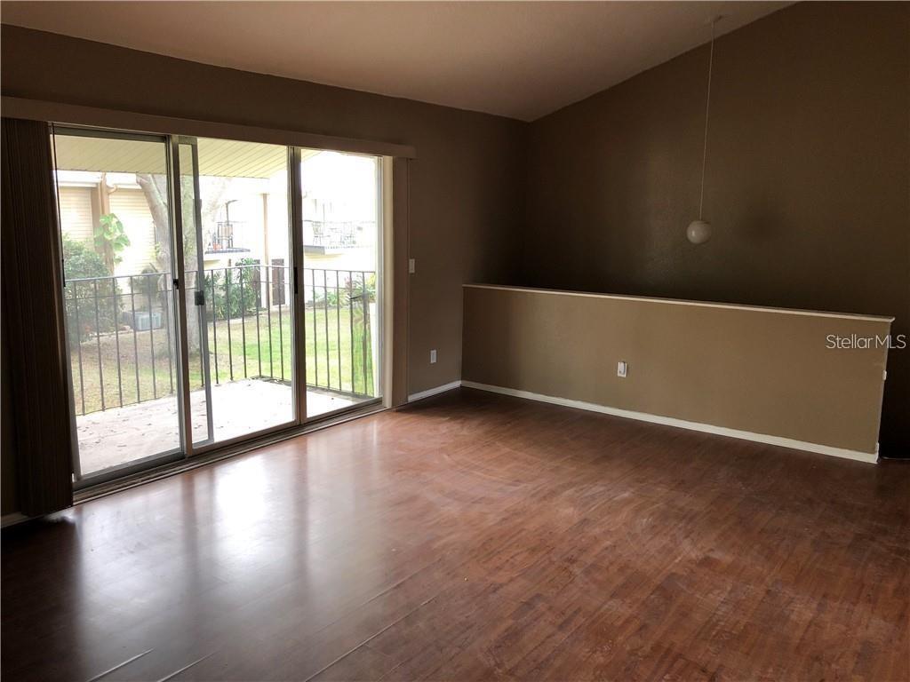A living room with wood-look flooring, a vaulted ceiling, and sliding glass doors to a balcony — 5453 SWEETWATER TERRACE CIRCLE, TAMPA, FL