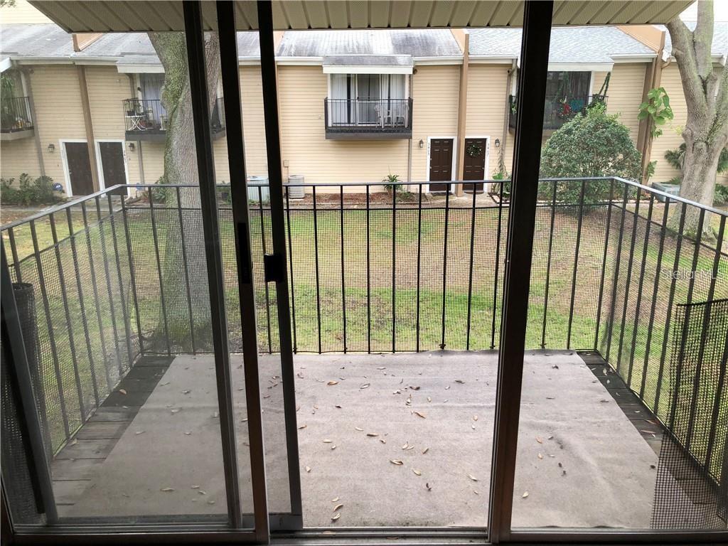 A view from inside through a sliding glass door onto a small, fenced balcony — 5453 SWEETWATER TERRACE CIRCLE, TAMPA, FL