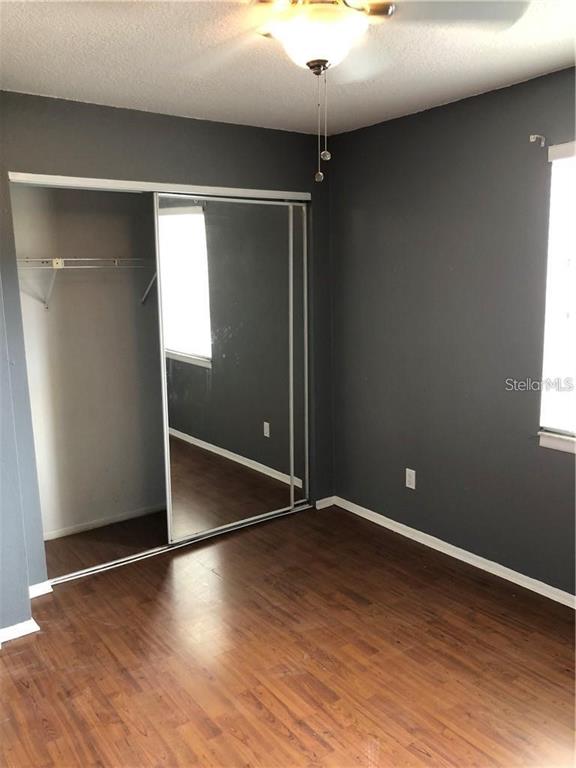 A bedroom features dark gray walls, wood-look flooring, and a sliding mirrored closet door — 5453 SWEETWATER TERRACE CIRCLE, TAMPA, FL
