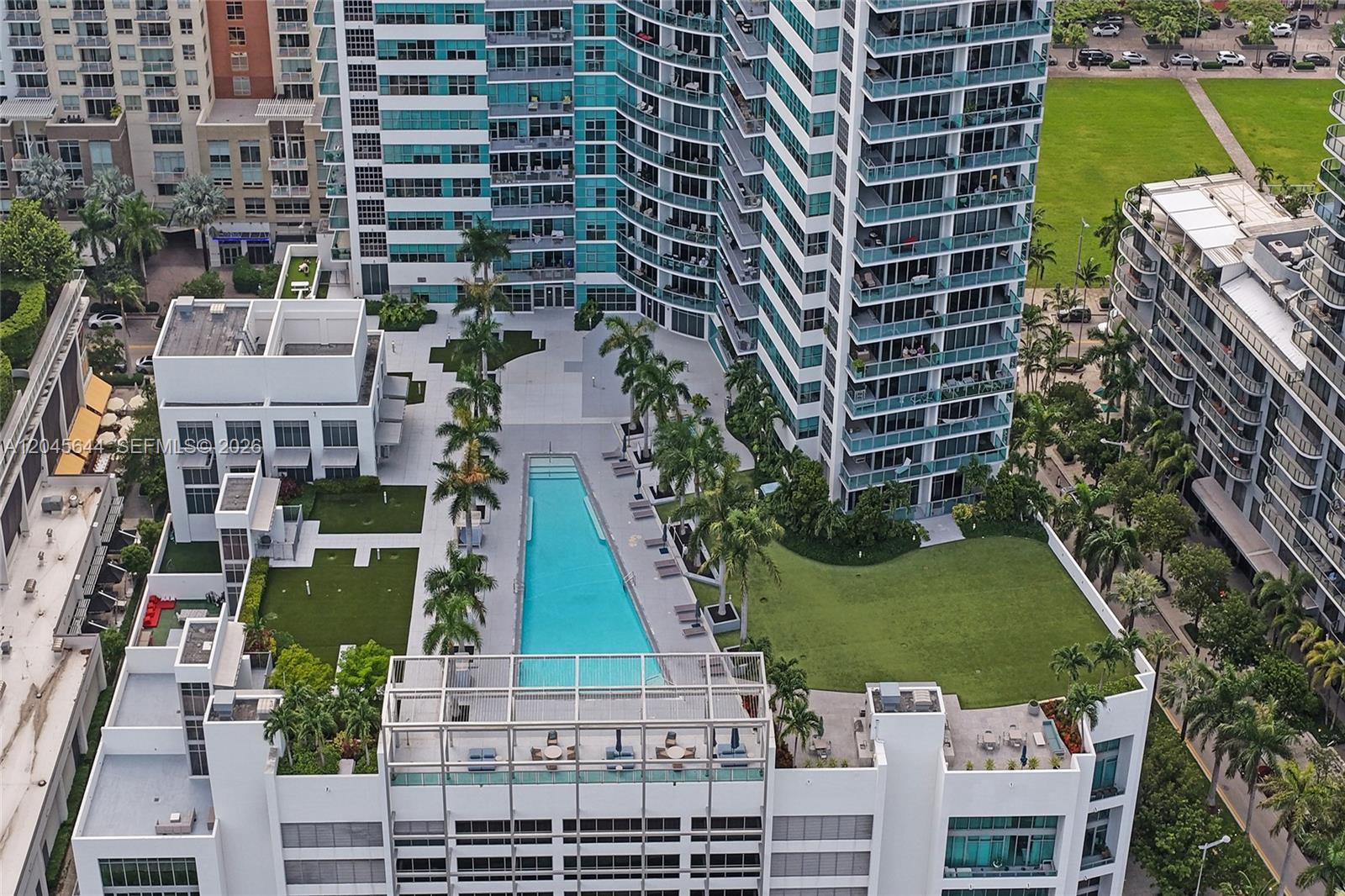 An aerial view shows a swimming pool surrounded by palm trees and apartment buildings — 3301 NE 1st Ave # H2405, Miami FL 33137, MIAMI, FL