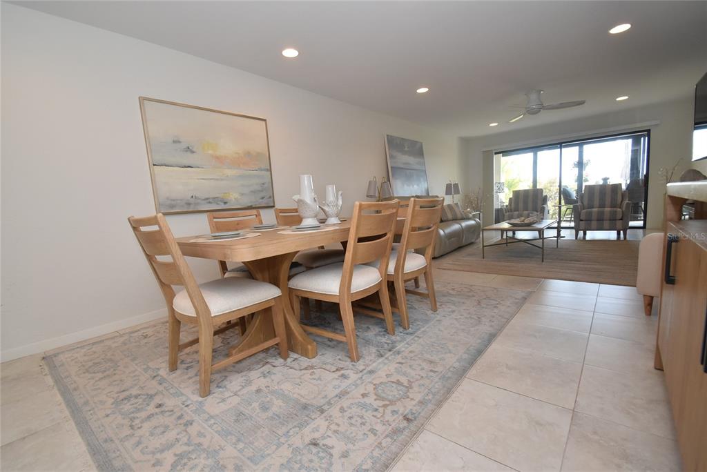 A dining area with a wooden table and chairs sits on a patterned area rug — 1510 PELICAN POINT DR UNIT BA168, SARASOTA, FL