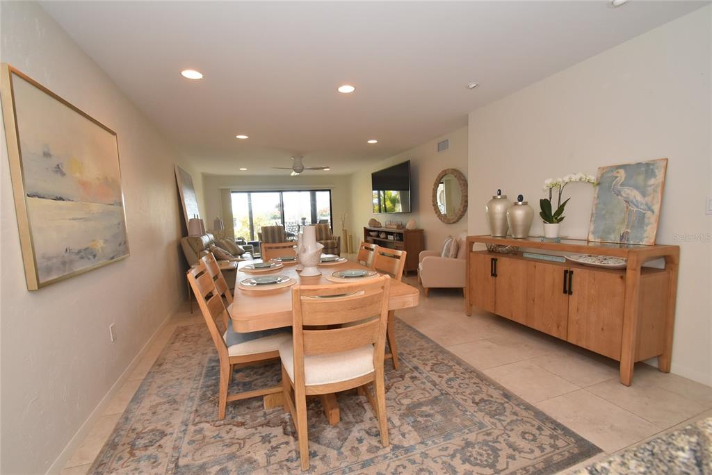 A dining room with a wooden table, chairs, and a sideboard on a patterned rug — 1510 PELICAN POINT DR UNIT BA168, SARASOTA, FL