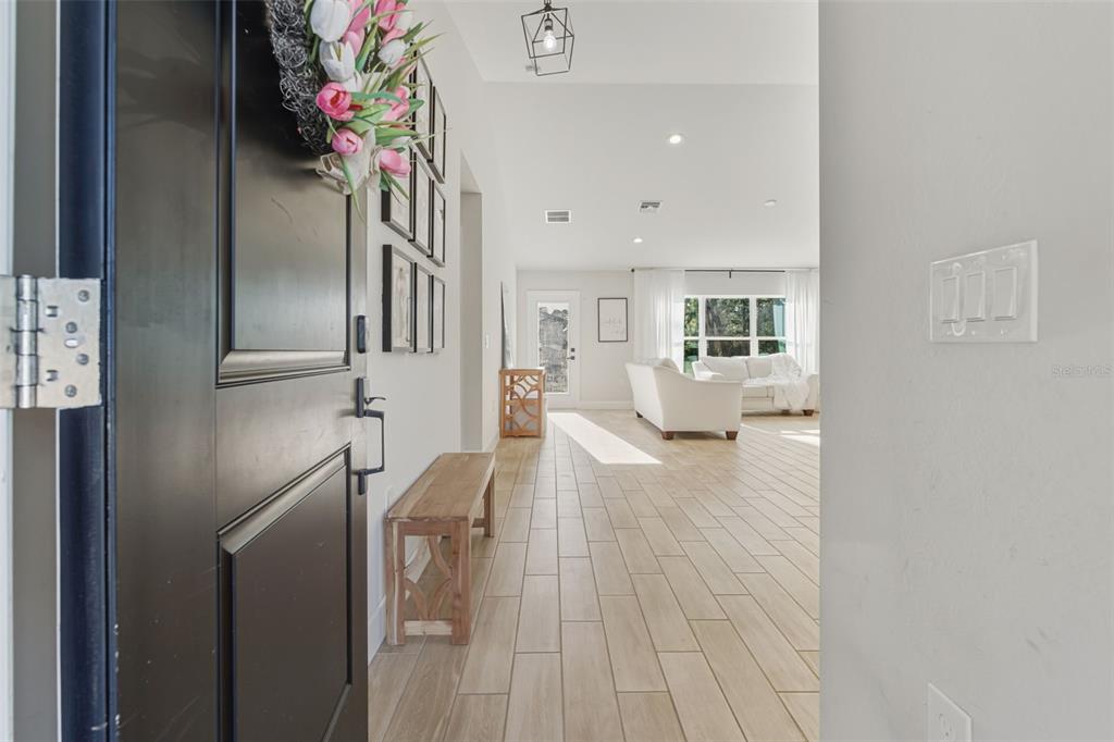 A view from an open front door into a bright living area with tiled floors — 1201 LOTUS STREET, PORT CHARLOTTE, FL