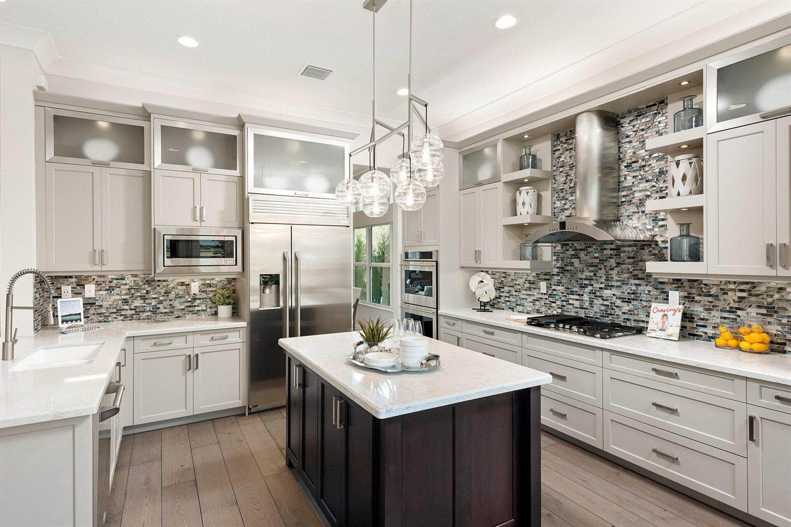 A modern kitchen features light gray cabinetry, a dark wood island, and a mosaic backsplash — 11219 Sweet Sage Avenue, Boynton Beach FL 33473, BOYNTON BEACH, FL