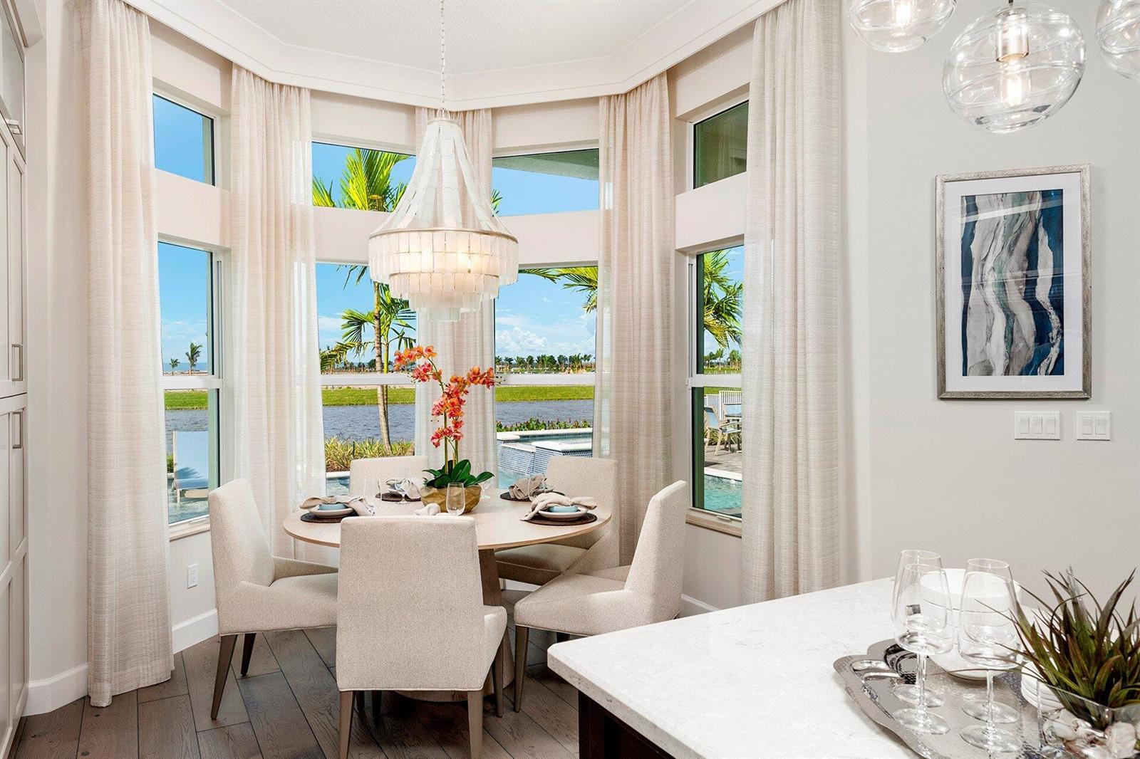 A dining area features a round table, four chairs, a chandelier, and large bay windows — 11219 Sweet Sage Avenue, Boynton Beach FL 33473, BOYNTON BEACH, FL