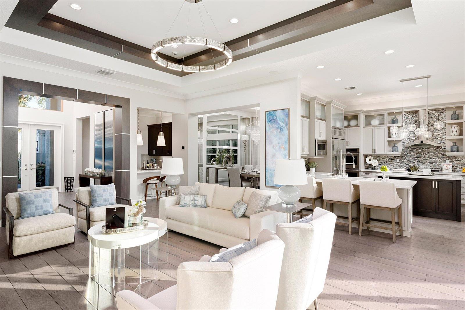 An open-concept living room and kitchen feature a coffered ceiling, neutral furniture, and wood flooring — 11219 Sweet Sage Avenue, Boynton Beach FL 33473, BOYNTON BEACH, FL