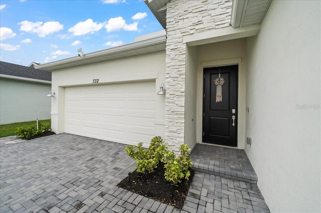 A house exterior features a white garage, a black front door, and stone facade accents — 732 VERIDIAN CIRCLE NW, PALM BAY, FL