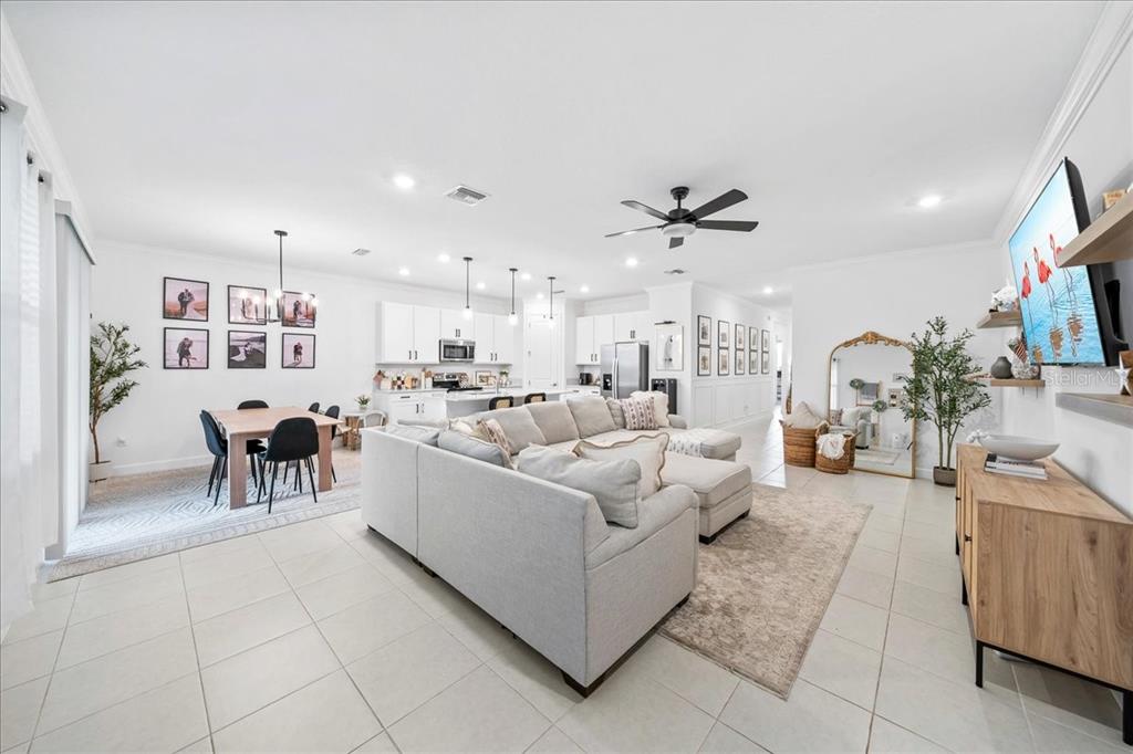 An open-concept living room and kitchen featuring white cabinetry, a sectional sofa, and tile flooring — 732 VERIDIAN CIRCLE NW, PALM BAY, FL