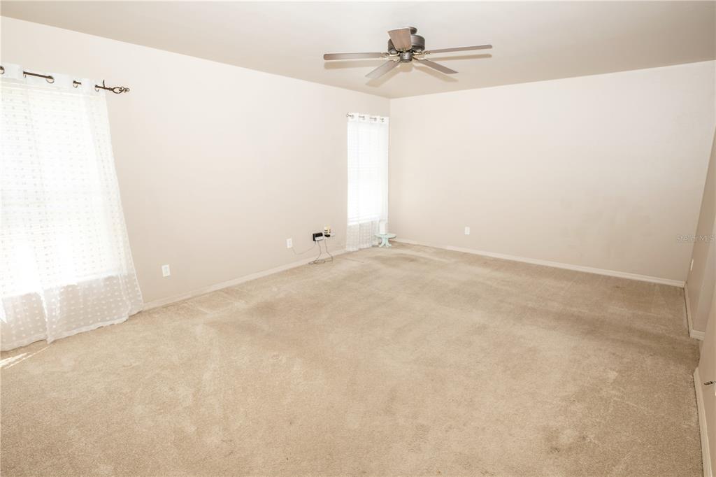 An empty bedroom features beige walls, light-colored carpeting, and a ceiling fan — 4129 NE 19TH PLACE, CAPE CORAL, FL