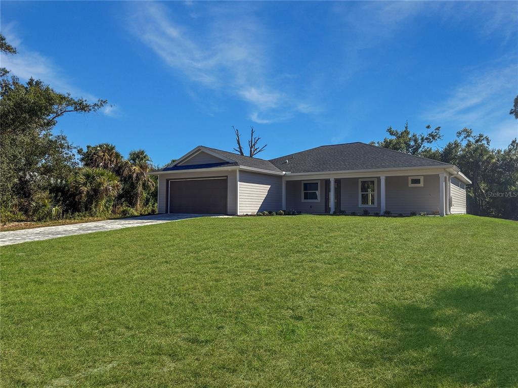 A single-story house with light gray siding, a two-car garage, and a large front lawn — 16419 STRAUSS AVENUE, PORT CHARLOTTE, FL