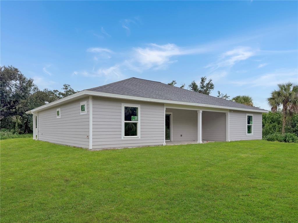 The exterior rear view of a light gray single-story house with a covered back porch — 16419 STRAUSS AVENUE, PORT CHARLOTTE, FL